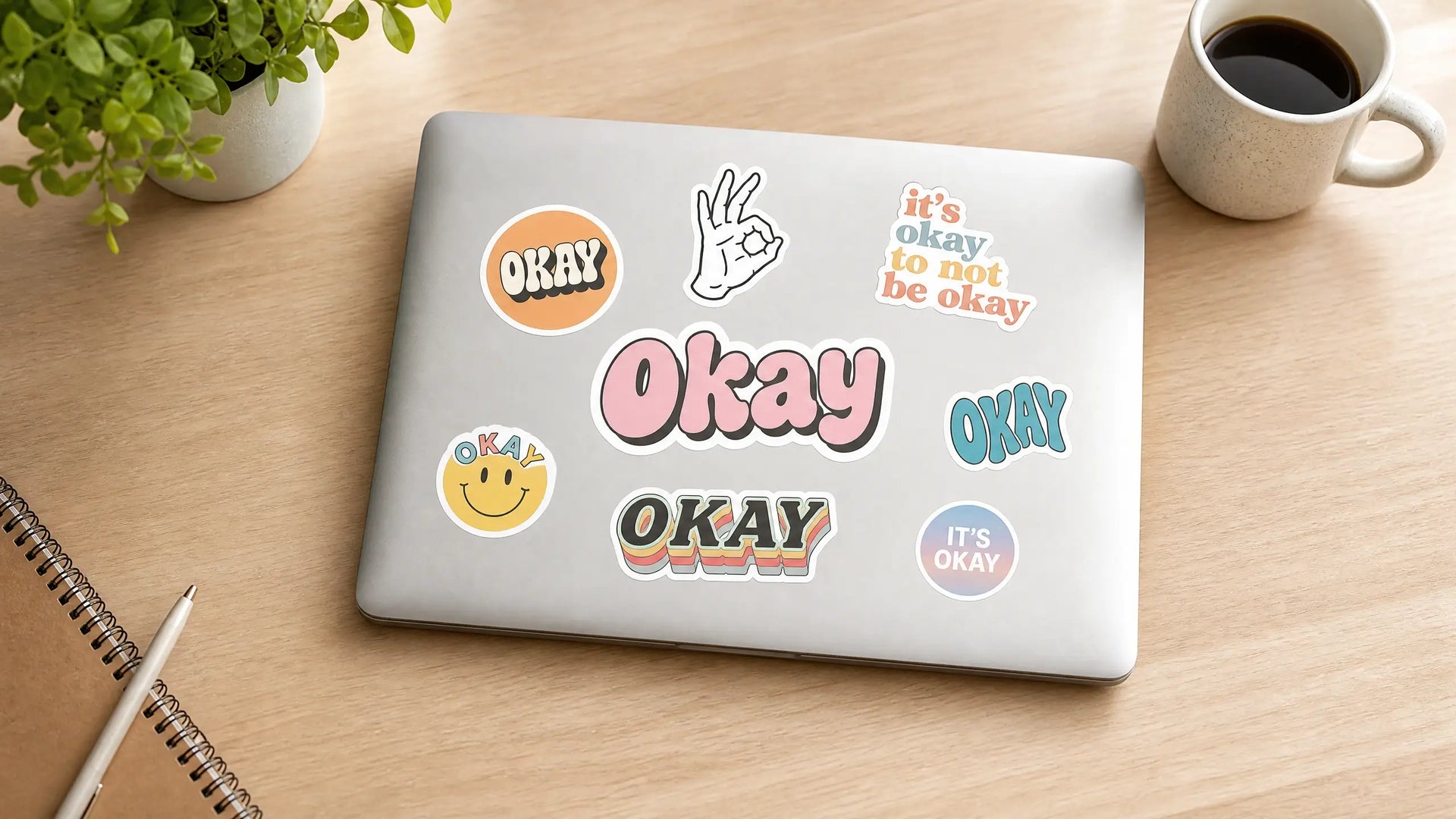 A collection of premium custom vinyl decals from Okay Stickers applied on a modern laptop cover, aesthetic lifestyle photography.