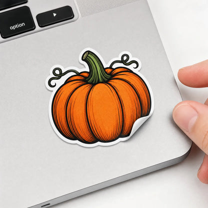 Custom die-cut pumpkin vinyl sticker applied on laptop corner with peeled edge detail