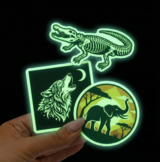 Glow in the dark vinyl stickers featuring crocodile skeleton, wolf illustration, and elephant silhouette, glowing green against black background