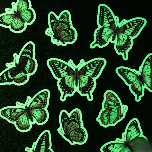 Glow in the dark butterfly vinyl stickers emitting green phosphorescent glow on black background