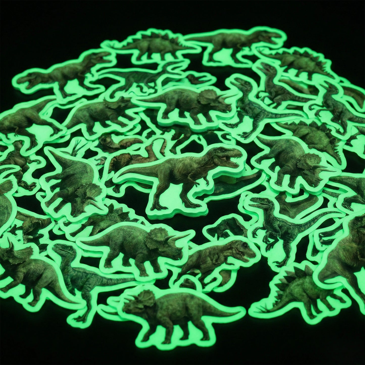Okaystickers Glow in the dark dinosaur vinyl stickers scattered on black background emitting green phosphorescent glow